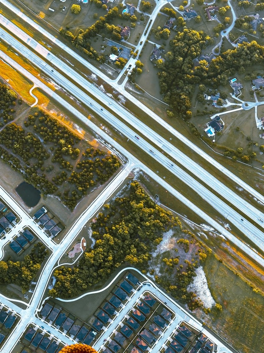 Aerial view of a suburban Texas neighborhood with single-family homes near a highway